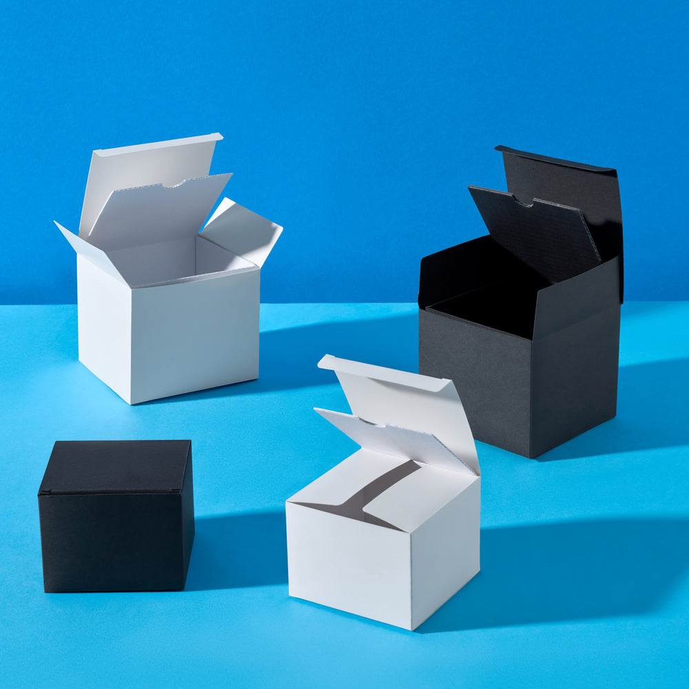 Luxury candle tin boxes in black and white on a blue background. 